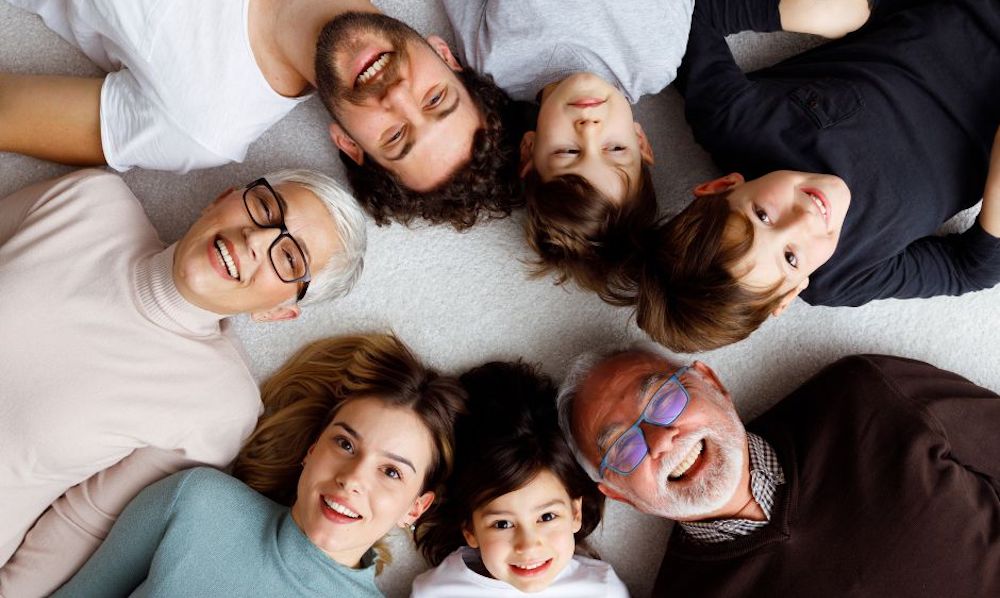 Navigating the World of High Net Worth Families/  Insights into Wealth, Legacy, and Success - A Family laying down in a circle looking up and smiling at the camera